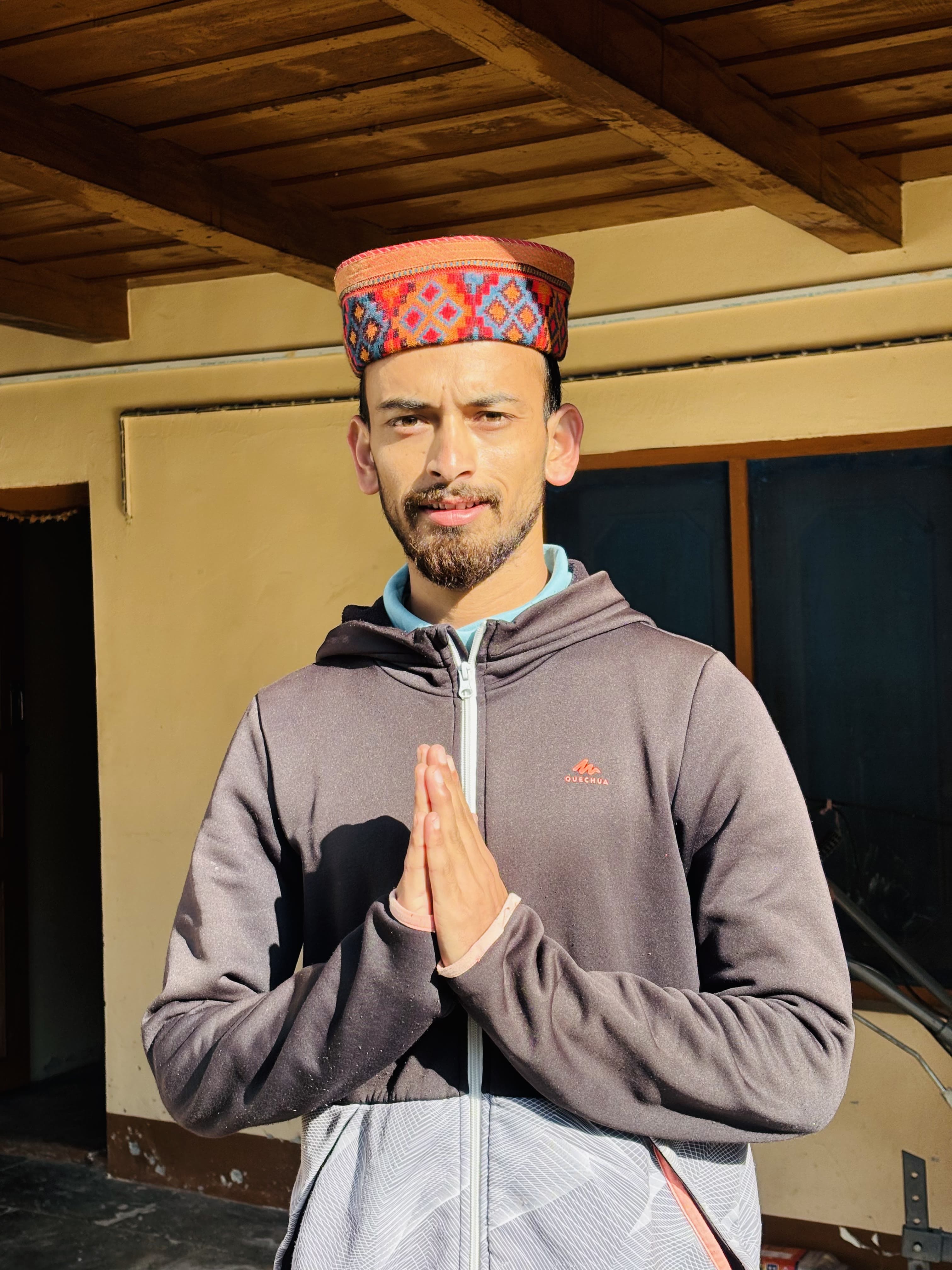Varun, your host at Varun Home Stay, in traditional Himachali topi with folded hands in namaste
